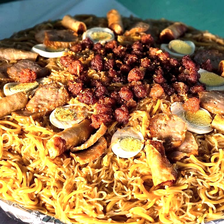 Pansit sa Bilao — party-size noodle tray with lumpia, egg, and meat toppings