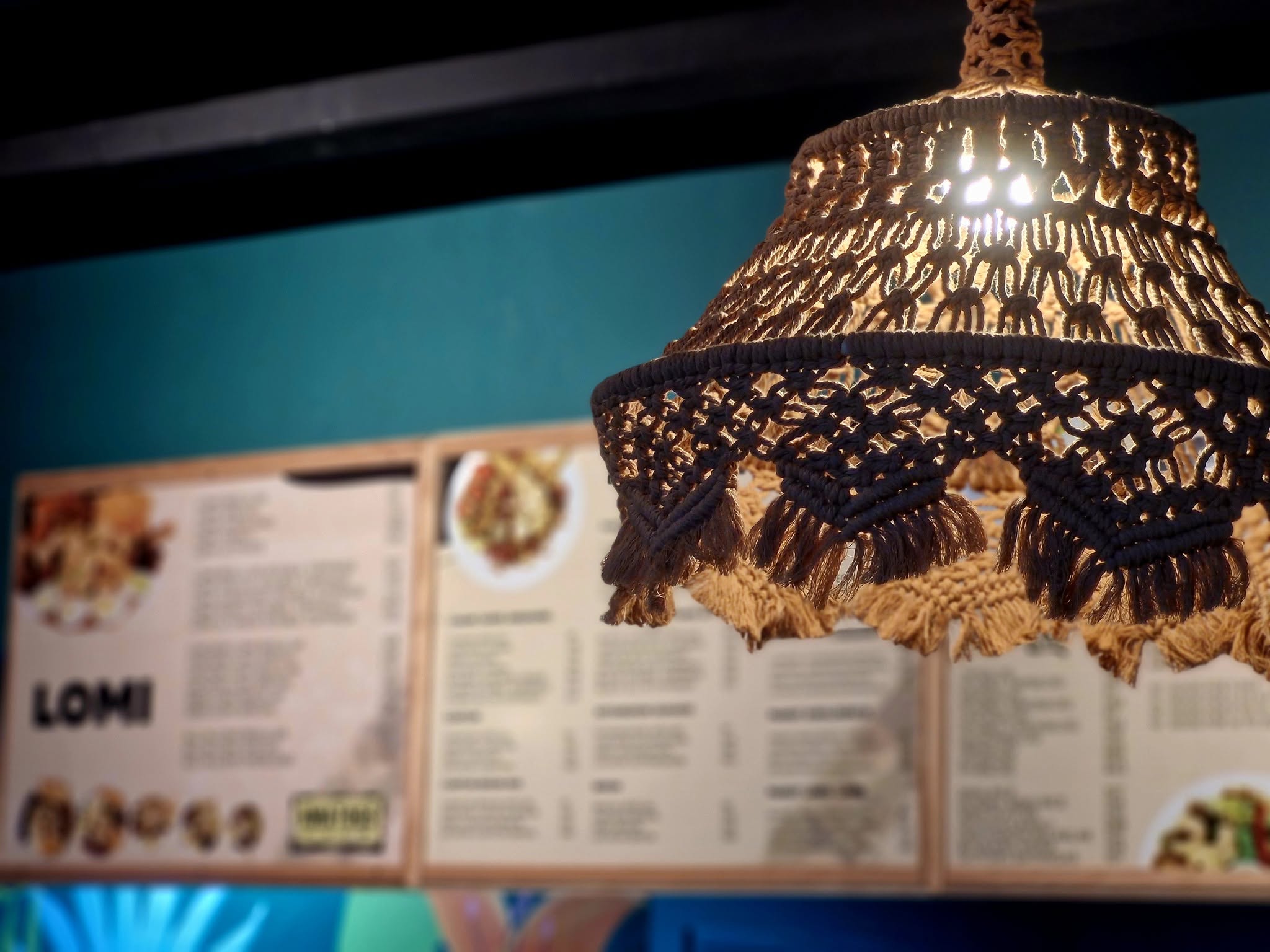 Inside a Kwatogs branch — woven pendant lamp over the Lomi menu boards